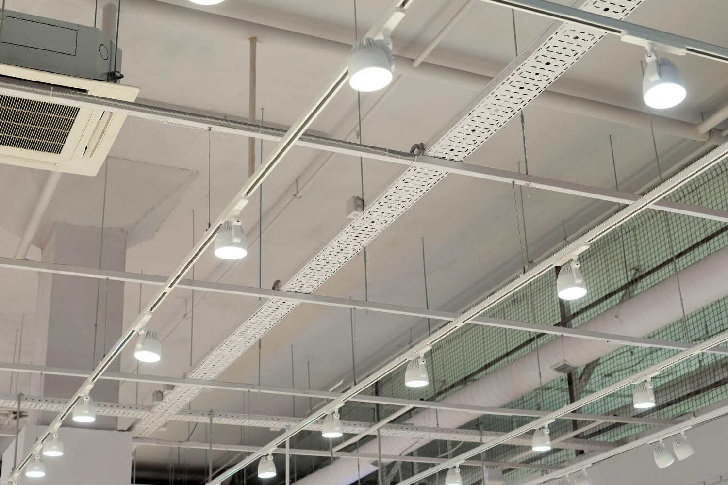 Ceiling-mounted lights and cable trays inside a large building.