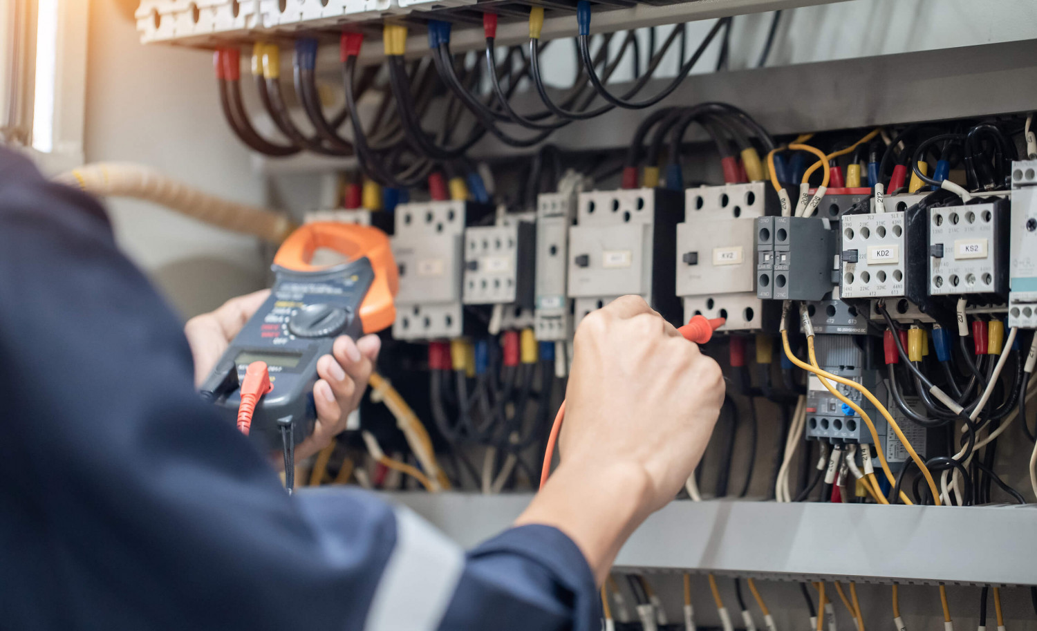 Electrical test equipment being used at a cabinet with wiring and contactors.